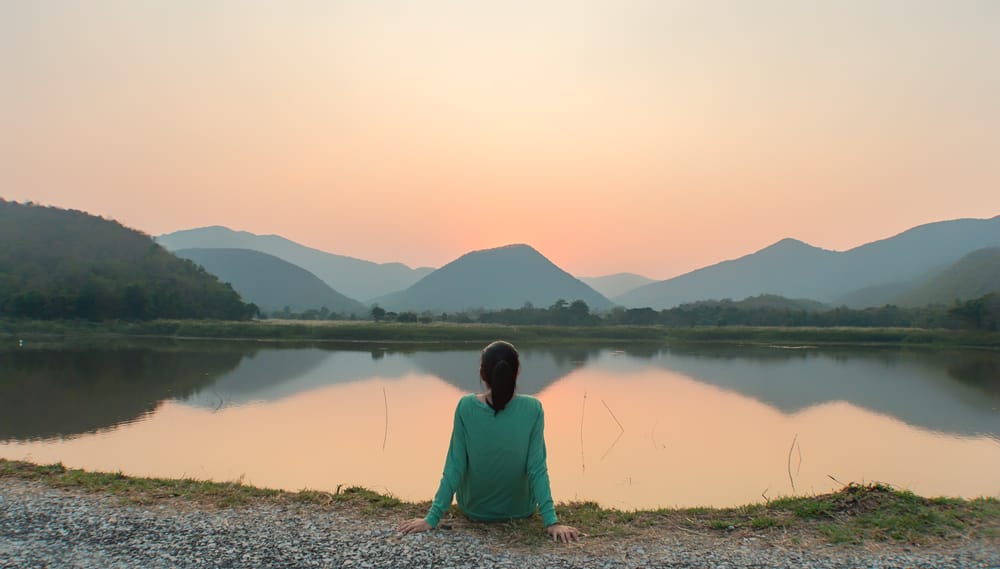 Meditation - Eating Disorder Solutions woman facing lake with mountains in background